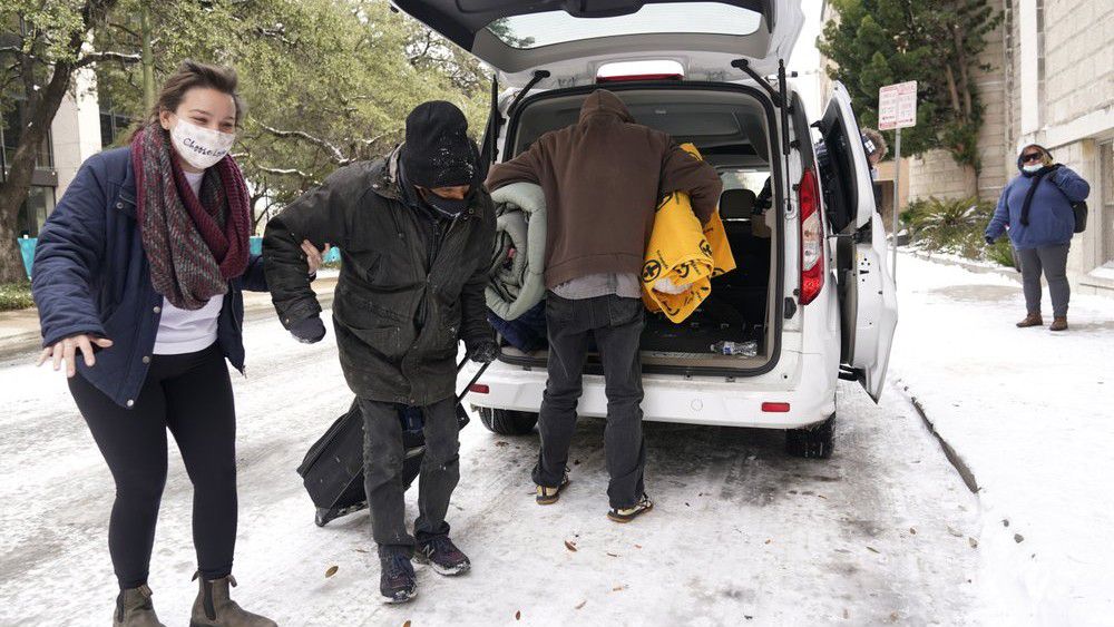 FILE - In this Feb. 16, 2021 file photo, Morgan Handley, left, helps move people to a warming shelter at Travis Park Methodist Church to help escape sub-freezing temperatures, in San Antonio. (Photo/Eric Gay, File)