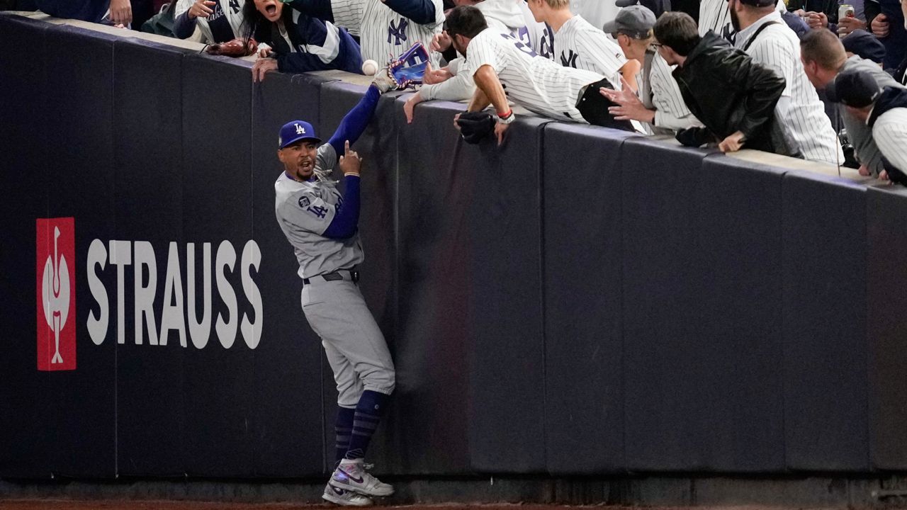 Fans interfere with a foul ball caught by Los Angeles Dodgers right fielder Mookie Betts during the first inning in Game 4 of the baseball World Series against the New York Yankees Tuesday in New York. (AP Photo/Ashley Landis)