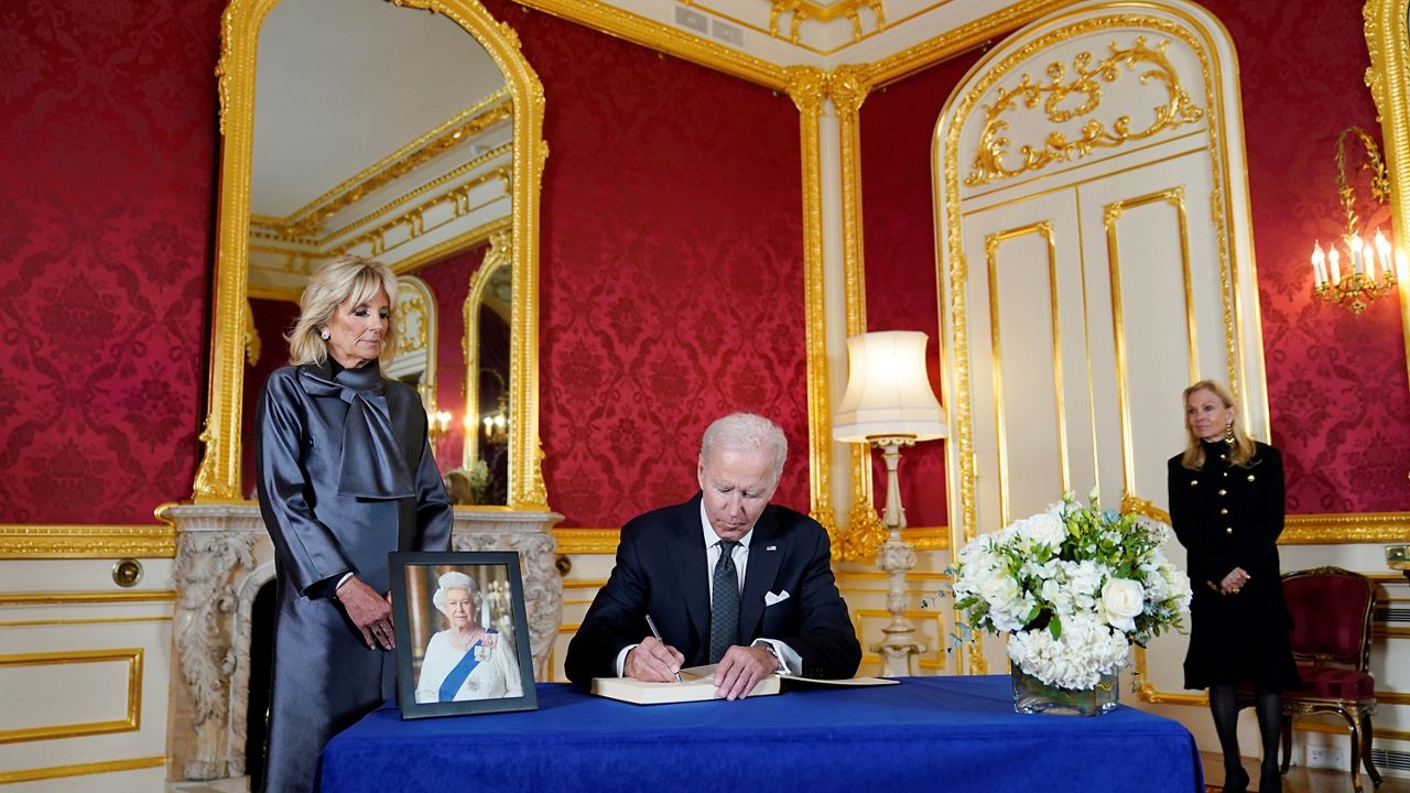 President Joe Biden signs a book of condolence at Lancaster House in London, following the death of Queen Elizabeth II, Sunday, Sept. 18, 2022, as first lady Jill Biden looks on, left, and T.H. Jane Hartley, Ambassador of the United States to the United Kingdom of Great Britain and Northern Ireland, looks on far right. (AP Photo/Susan Walsh)
