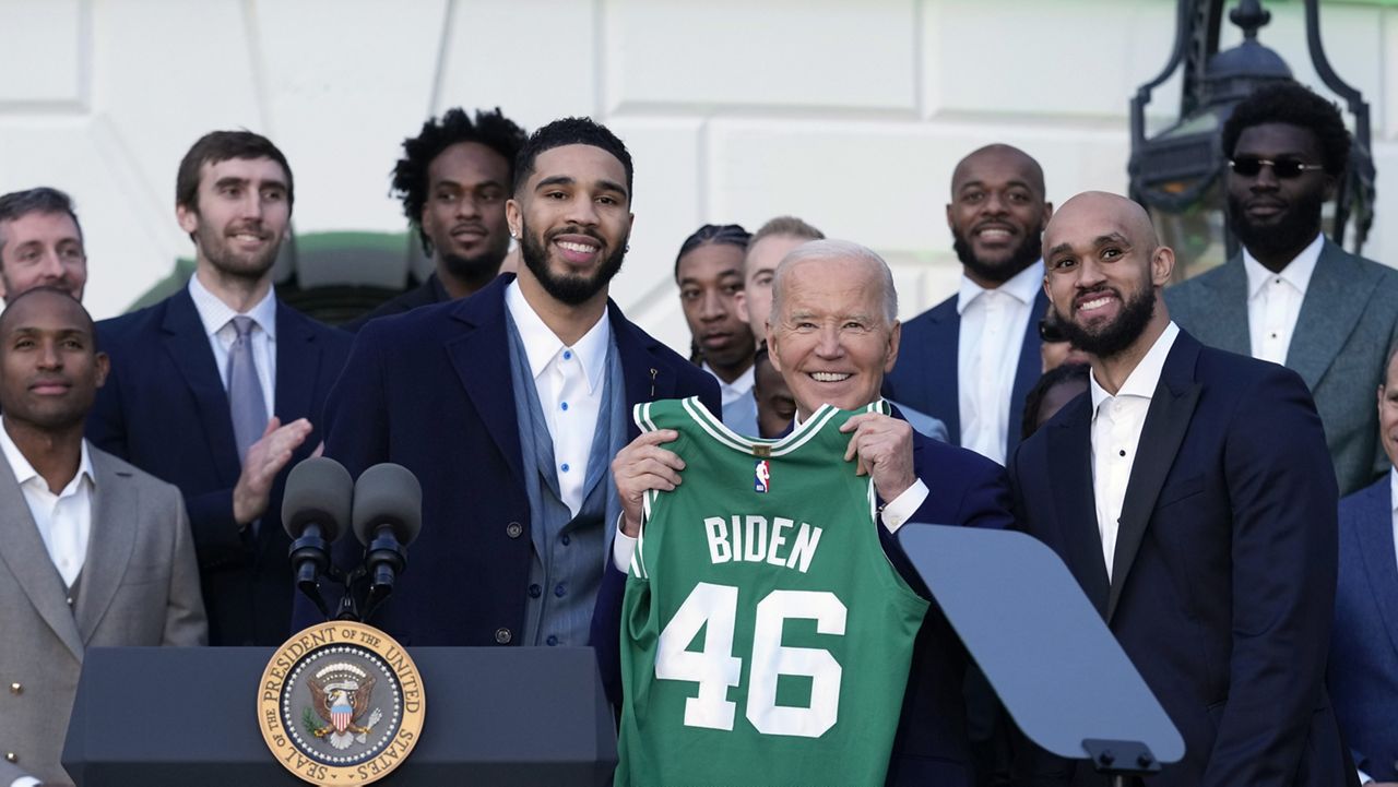 President Joe Biden, center, flanked by Boston Celtics players Jayson Tatum, left, and Derrick White, holds up a jersey they presented to him during an event to celebrate the team's victory in the 2024 National Basketball Association Championship, on the South Lawn of the White House in Washington, Thursday, Nov. 21, 2024. (AP Photo/Susan Walsh)