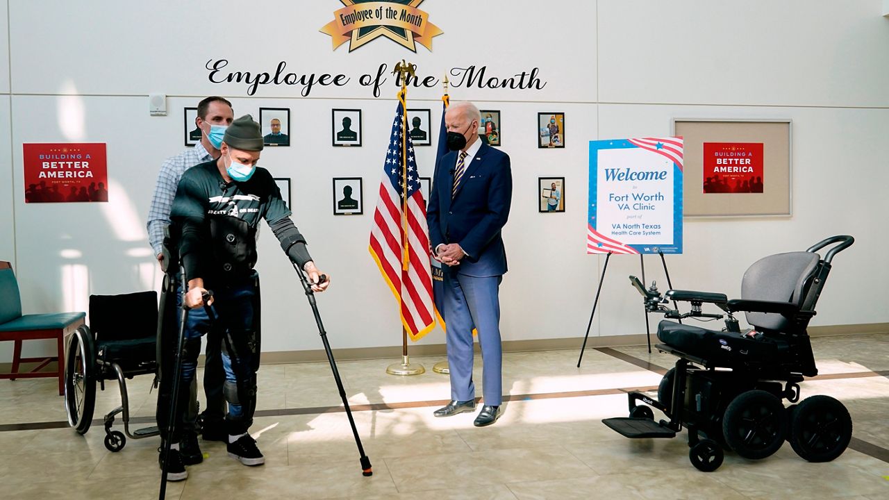 President Joe Biden watches as veteran John Caruso walks with the help of an exoskeleton and is assisted by Joshua Geering, SCI Therapy Lead Therapist, Spinal Cord Injury/Disabilities Center in Dallas, as Biden tour's the Fort Worth VA Clinic in Fort Worth, Texas, Tuesday, March 8, 2022.