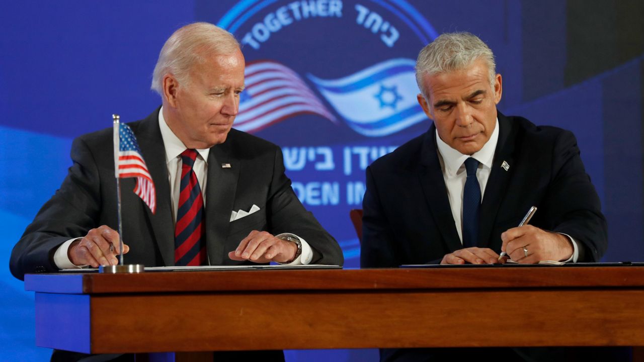 President Joe Biden, left, and Israeli Prime Minister Yair Lapid sign a security pledge Thursday in Jerusalem. (Atef Safadi/Pool via AP)