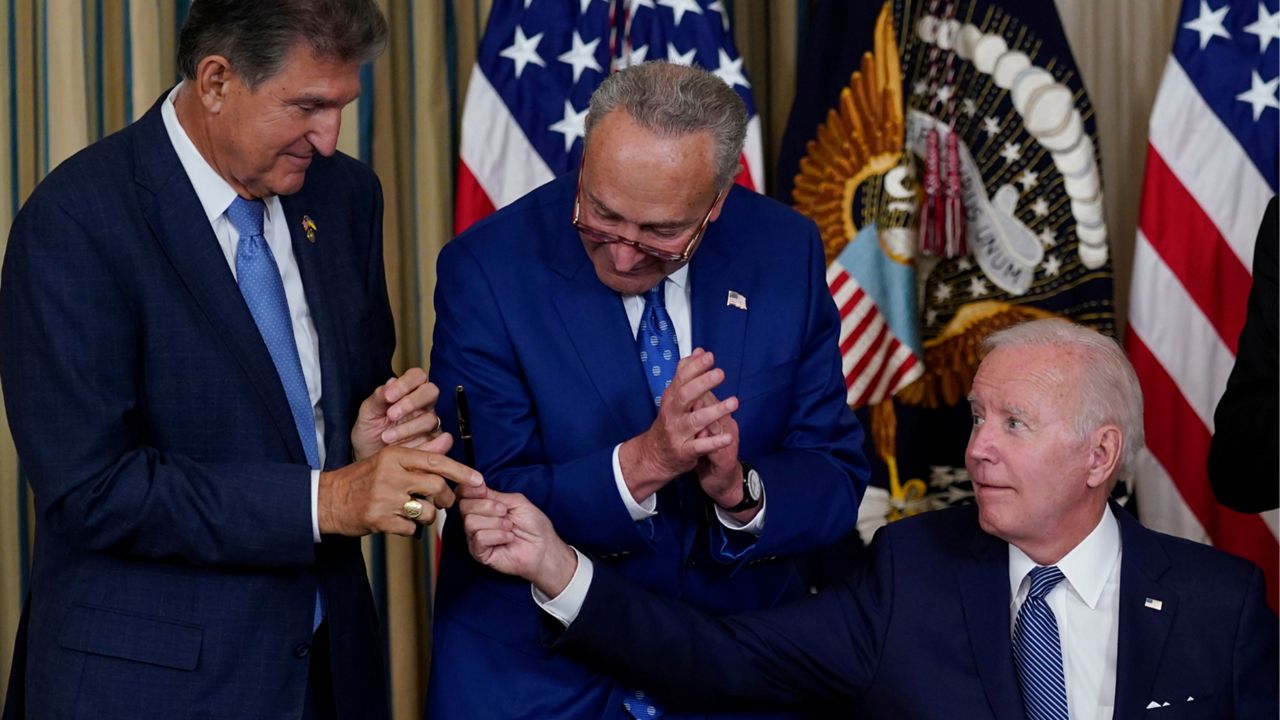 President Joe Biden hands the pen he used to sign the Democrats' landmark climate change and health care bill to Sen. Joe Manchin, D-W.Va., as Senate Majority Leader Chuck Schumer of N.Y., watches in the State Dining Room of the White House in Washington, Aug. 16, 2022. Manchin made a deal with Democratic leaders as part of his vote pushing the party's highest legislative priority across the finish line last month. Now, he's ready to collect. But many environmental advocacy groups and lawmakers are balking. (AP Photo/Susan Walsh, File)