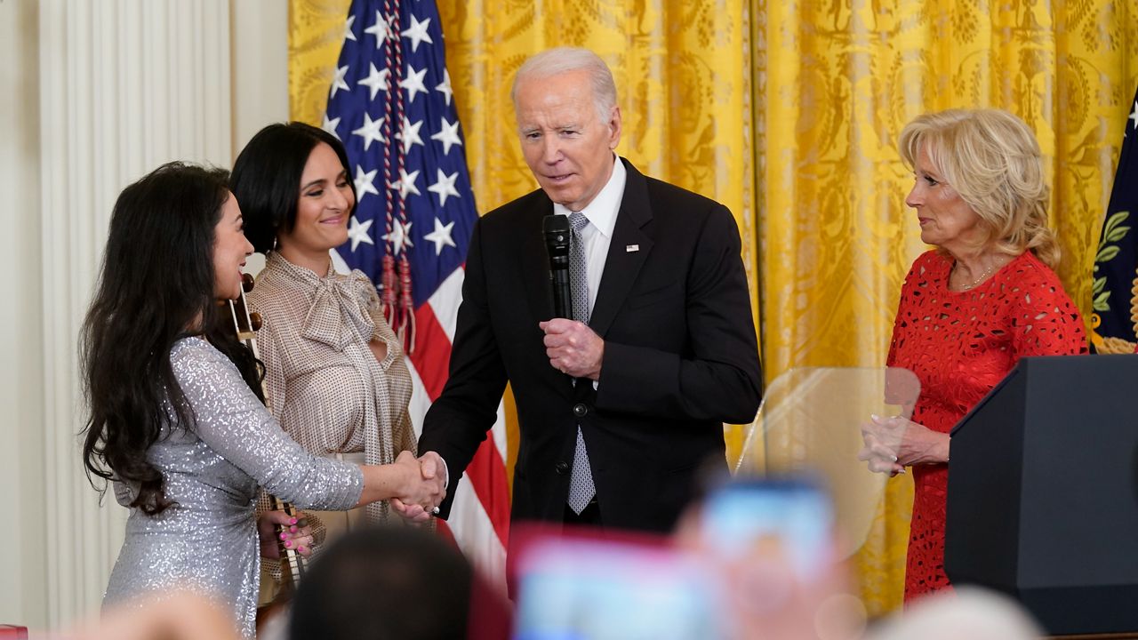 President Joe Biden, accompanied by first lady Jill Biden, shakes hands with performer Sahba Motallebi, left, as he speaks during a Nowruz celebration in the East Room of the White House, Monday, March 20, 2023, in Washington. Rana Mansour, an Iranian-American singer-songwriter, is second from left. (AP Photo/Evan Vucci)