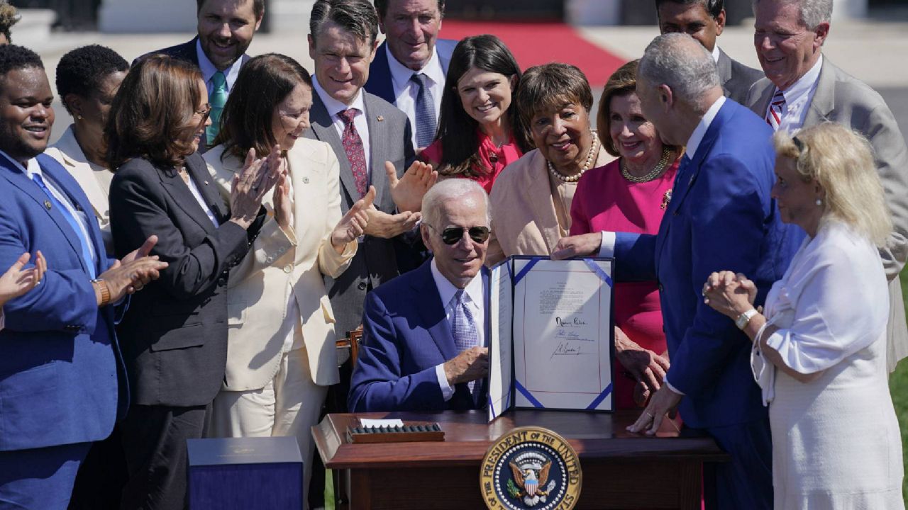 President Joe Biden holds the "CHIPS and Science Act of 2022" after signing it during a ceremony on the South Lawn of the White House, Tuesday, Aug. 9, 2022, in Washington. (AP Photo/Evan Vucci)