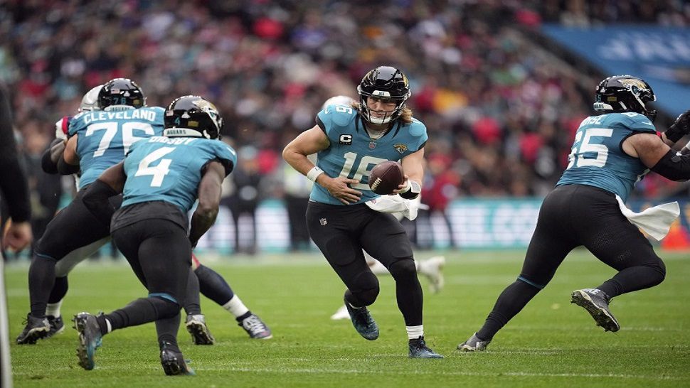 Jacksonville Jaguars quarterback Trevor Lawrence (16) hands off to running back Tank Bigsby (4) during the first half of an NFL football game against the New England Patriots, Sunday, Oct. 20, 2024, in London. (AP Photo/Kin Cheung)