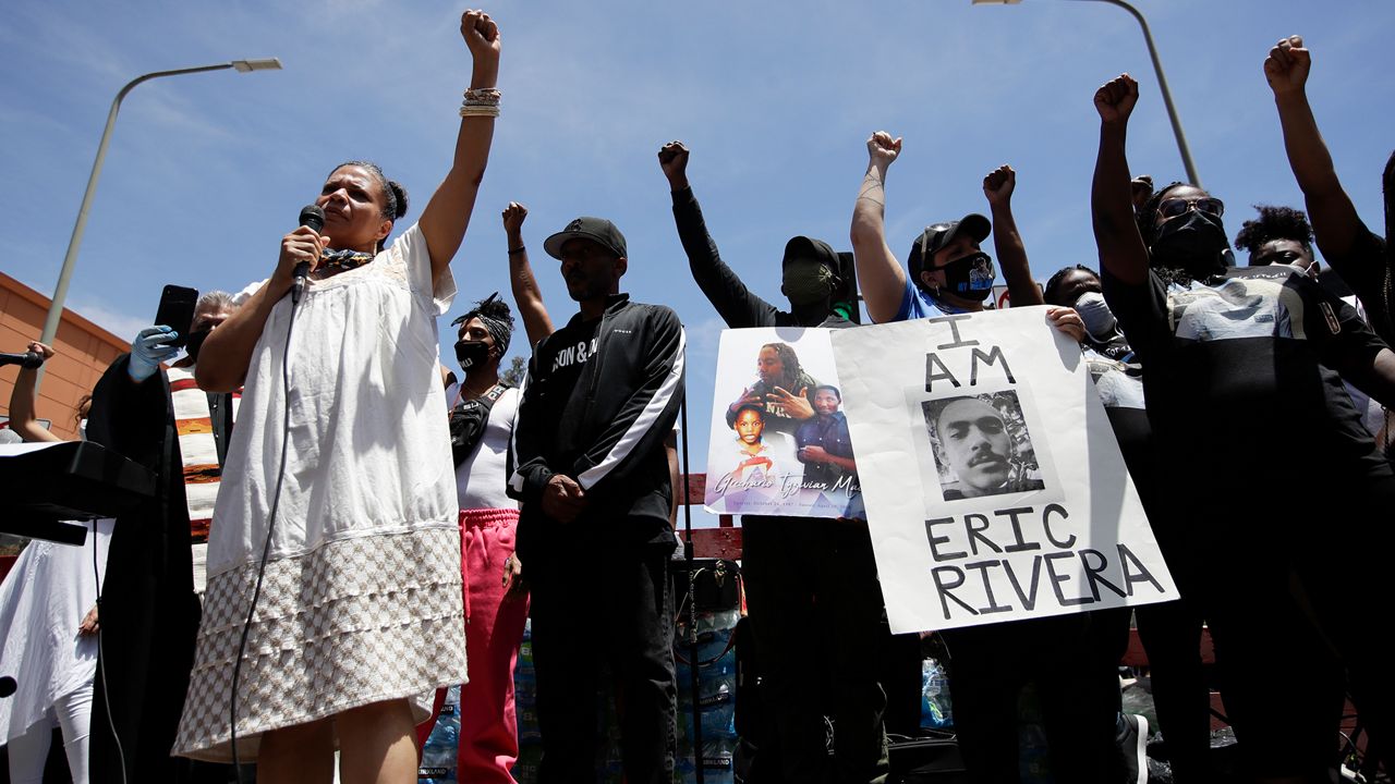 Melina Abdullah, left, of Black Lives Matter Los Angeles, leads a crowd in a raising of fists Monday, June 8, 2020, in Los Angeles during a protest over the death of George Floyd who died May 25 after he was restrained by Minneapolis police.. (AP Photo/Marcio Jose Sanchez)