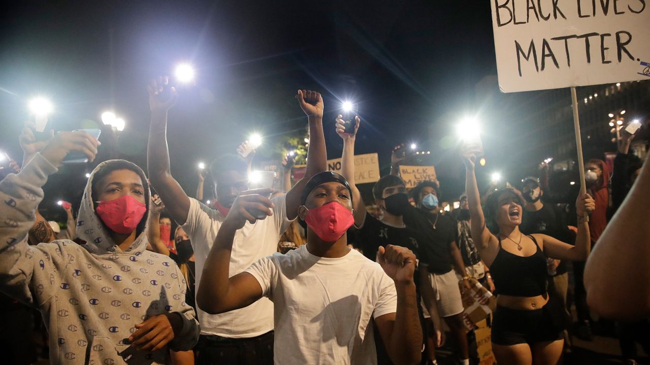 Demonstrators use their phone lights Wednesday, June 3, 2020 in downtown Los Angeles during a protest over the death of George Floyd who died May 25 after he was restrained by Minneapolis police. (AP Photo/Marcio Jose Sanchez)