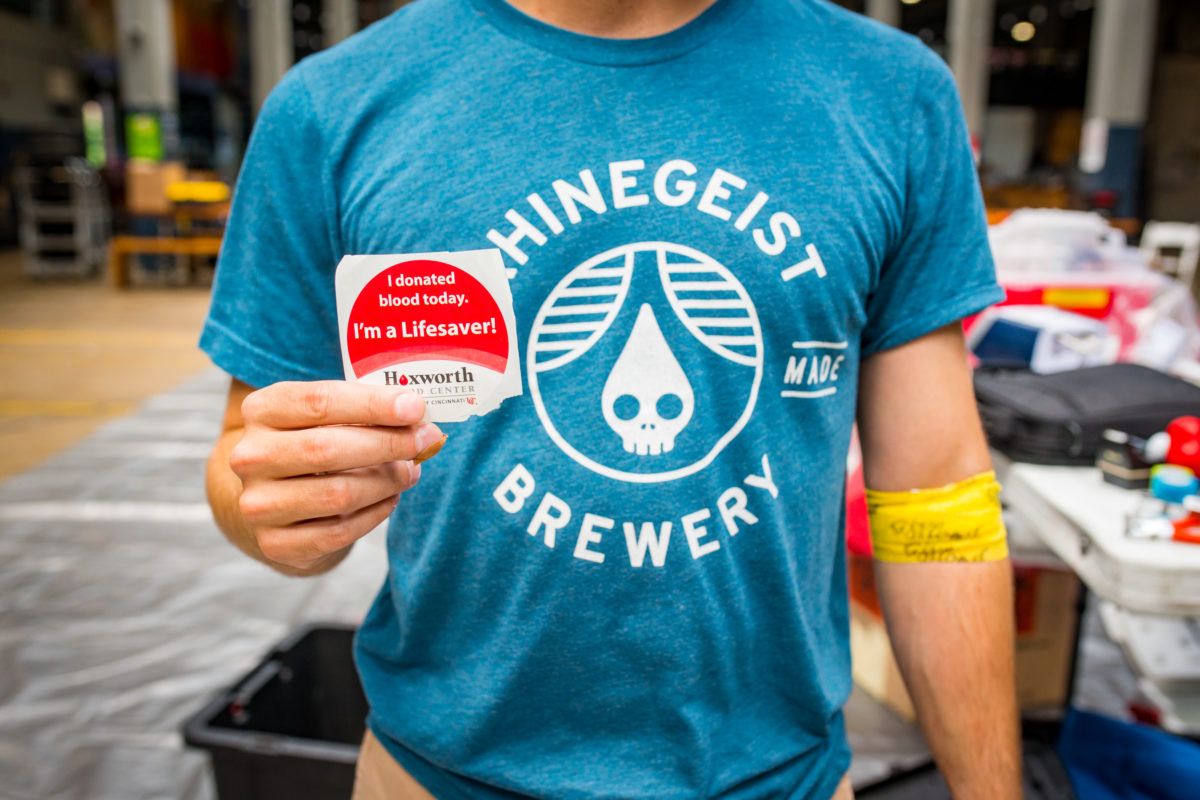 A person in a Rhinegeist Brewery t-shirt poses for a picture with a stick after donating blood. (Photo courtesy of Rhinegeist Brewery)