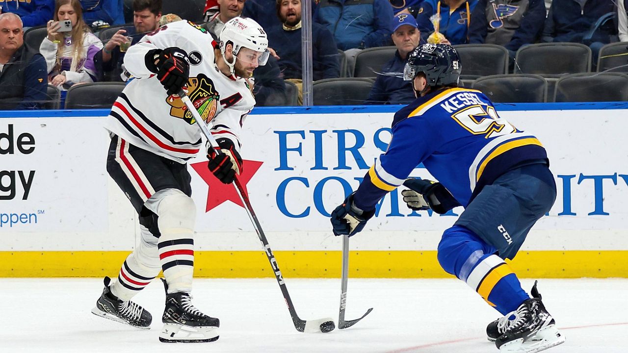 Chicago Blackhawks' Jason Dickinson (16) passes the puck while under pressure from St. Louis Blues' Matthew Kessel (51) during the third period of an NHL hockey game Wednesday, April 10, 2024, in St. Louis. (AP Photo/Scott Kane)