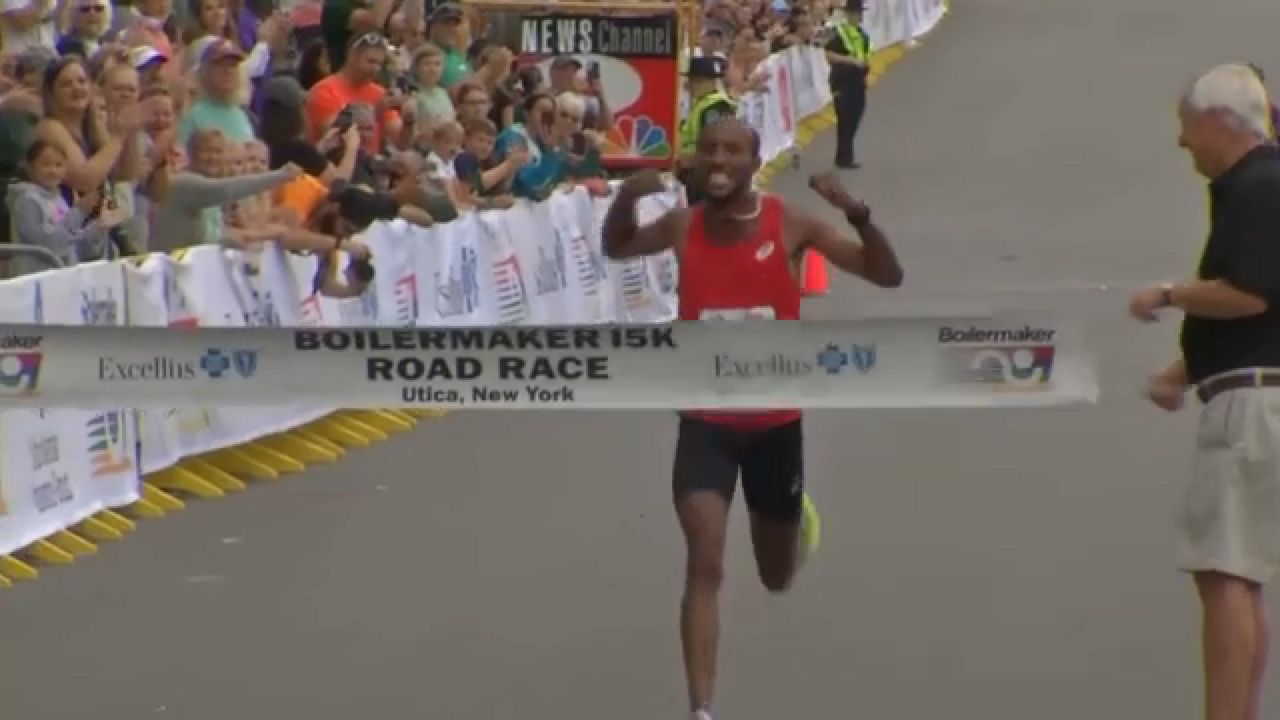 boilermaker 15k winner crosses finish line, arms raised in victory
