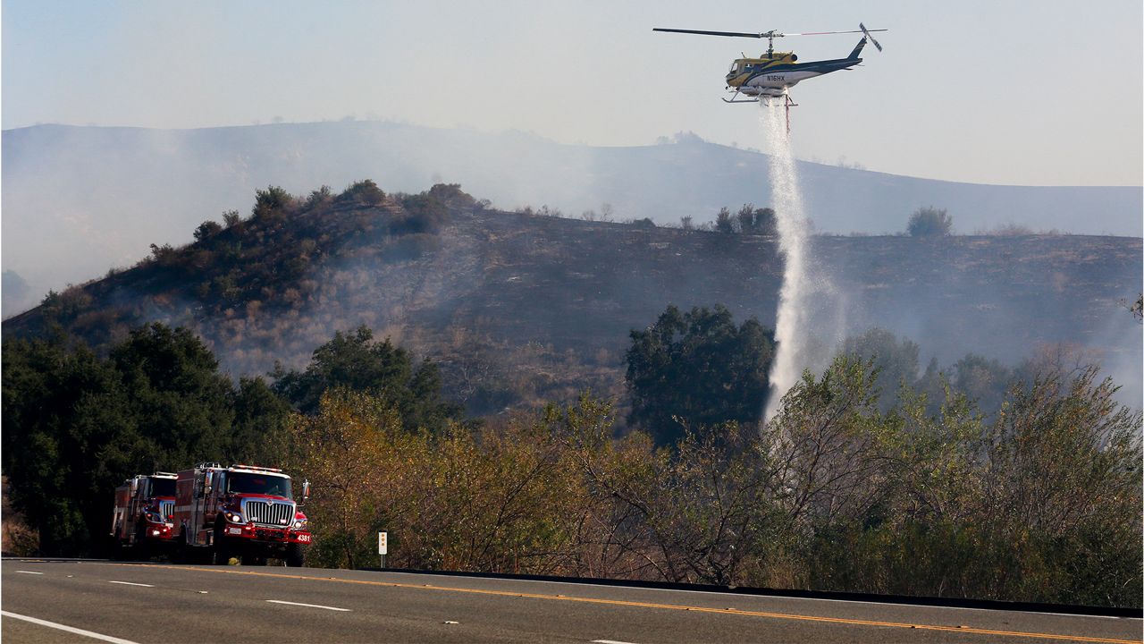 A helicopter drops water at the Bond Fire burning in Silverado, Calif., on Thursday, Dec. 3, 2020. (AP Photo/Ringo H.W. Chiu)