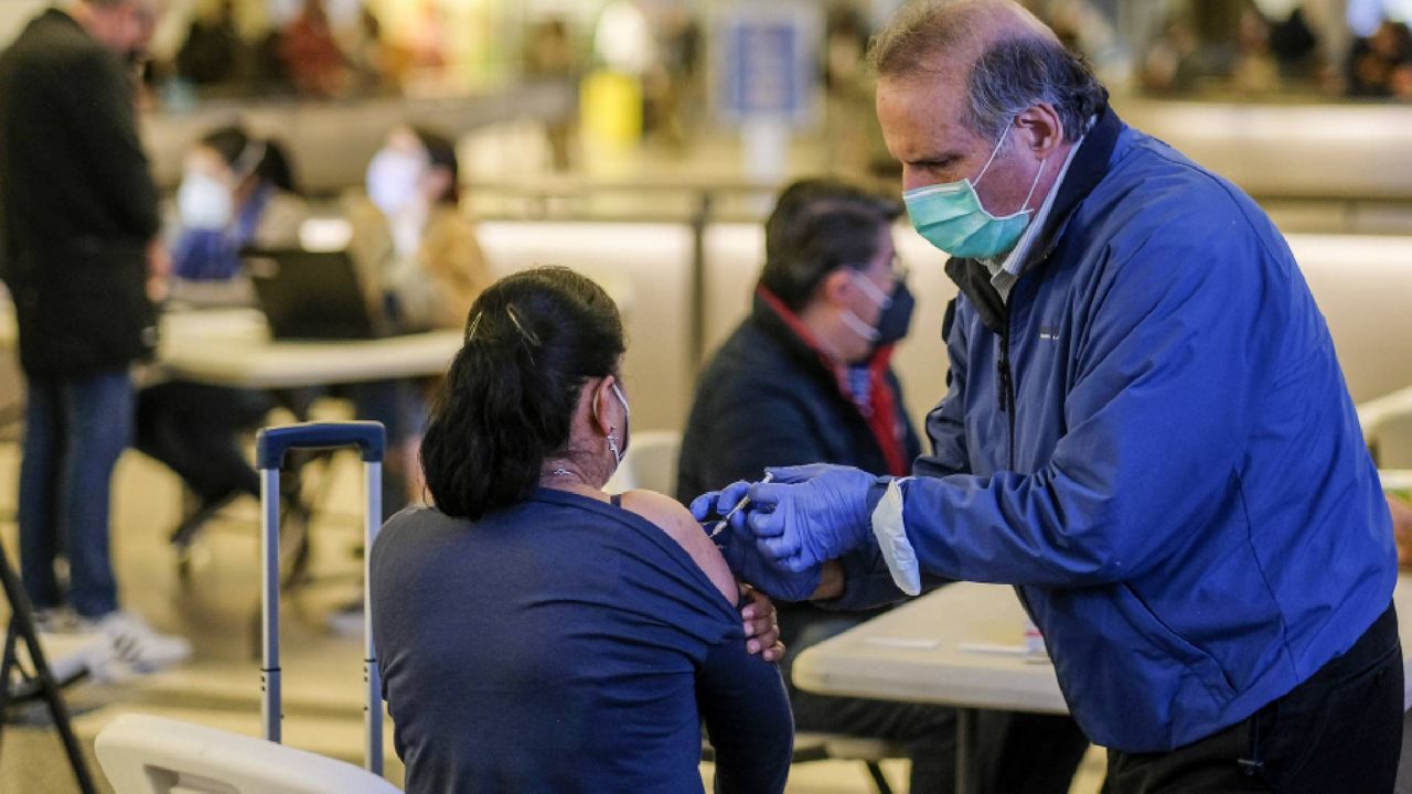 A traveler is vaccinated at the Los Angeles International Airport in Los Angeles, Wednesday Dec. 22, 2021. (AP Photo/Ringo H.W. Chiu)