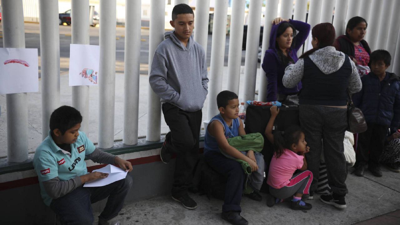 FILE - In this Sept. 13, 2019, file photo, Central American migrants wait to see if their number will be called to cross the border and apply for asylum in the United States, at the El Chaparral border crossing in Tijuana, Mexico. (AP Photo/Emilio Espejel, File)