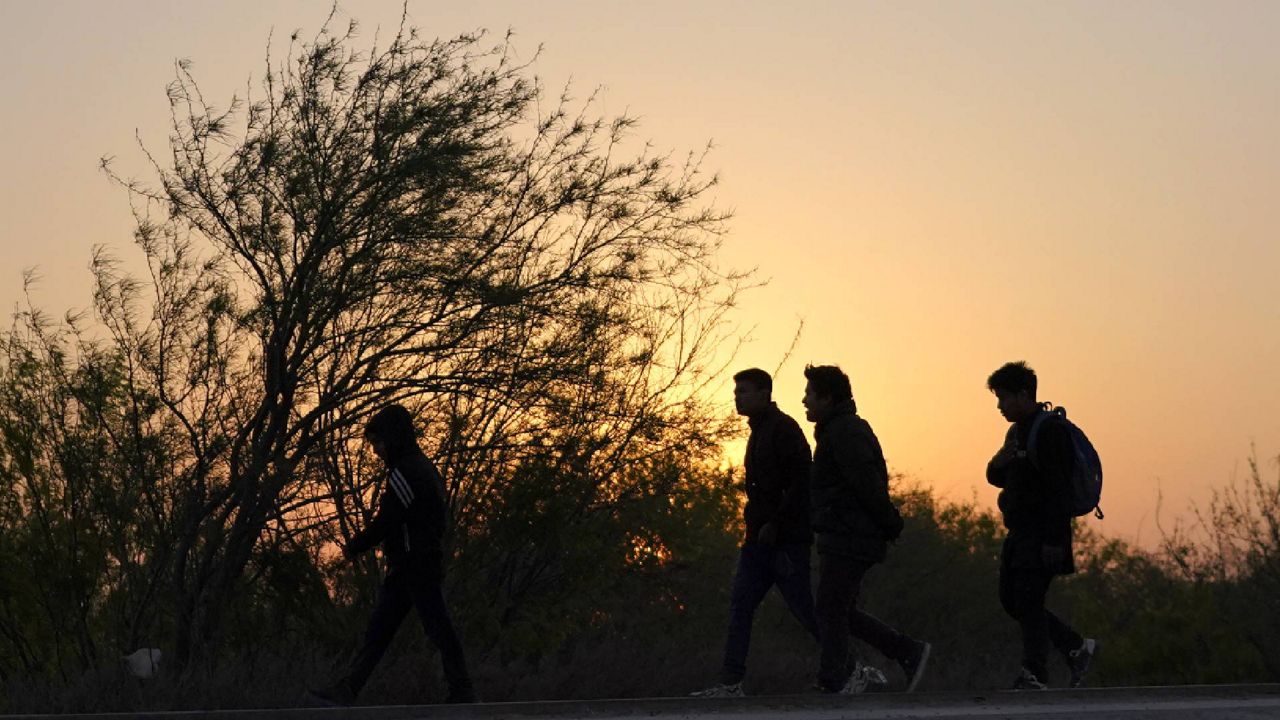 Migrants walk near a gate on the U.S.-Mexico border wall after they were spotted by a U.S. Customs and Border Protection agent and taken into custody while trying to cross, Sunday, March 21, 2021, in Abram-Perezville, Texas. (AP Photo/Julio Cortez)