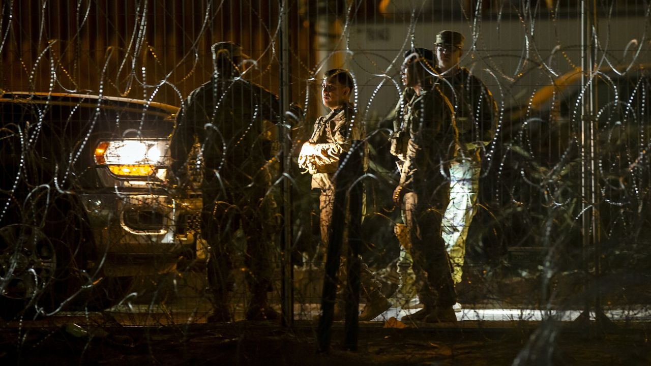 Texas Army National Guard members talk while patrolling behind razor wire on the banks of the Rio Grande in El Paso, Texas, seen from Ciudad Juarez, Mexico, late Thursday, Aug. 8, 2024. (AP Photo/Andres Leighton)