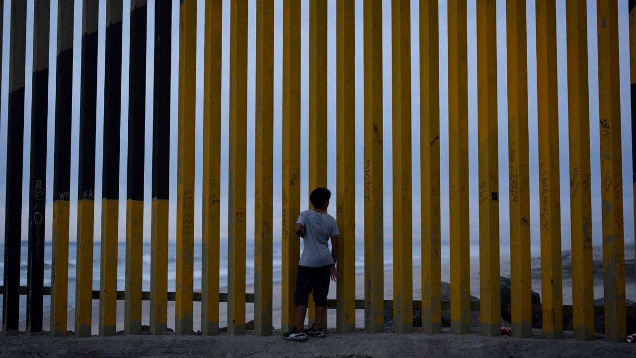 A boy looks through a border wall separating Mexico from the United States, Nov. 26, 2024, in Tijuana, Mexico. (AP Photo/Gregory Bull, File)