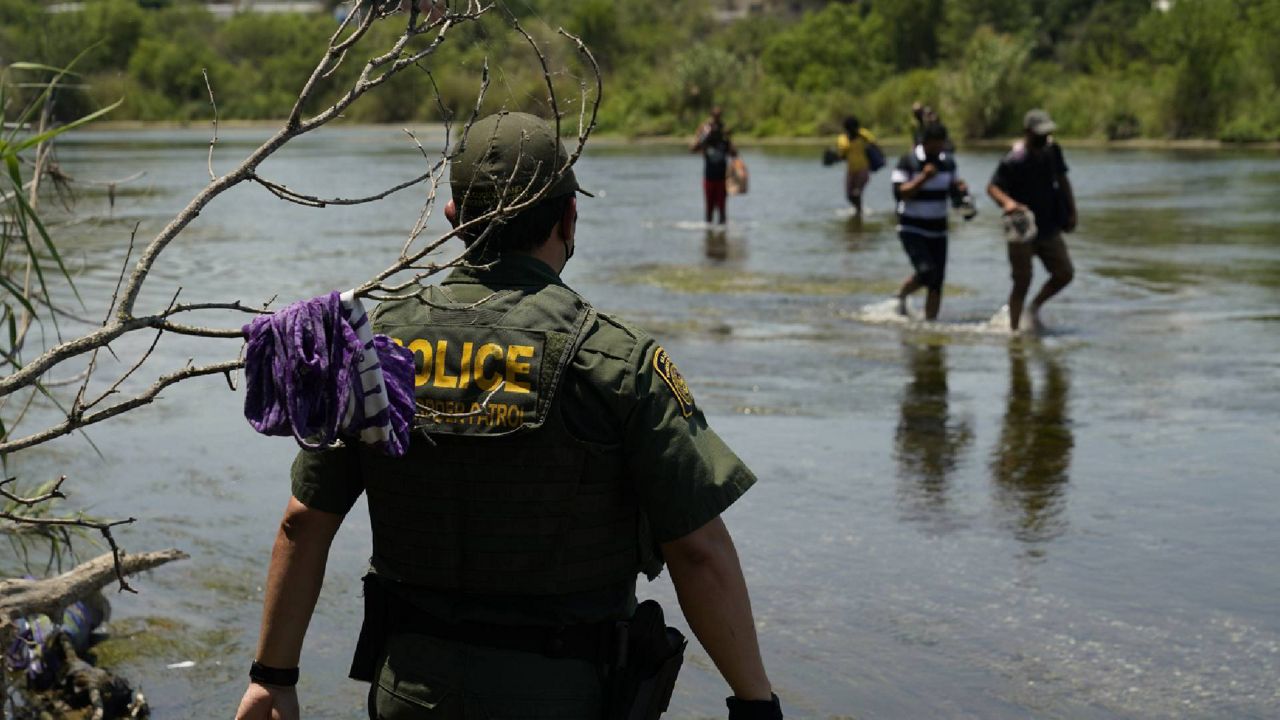 FILE - In this June 15, 2021, file photo, a Border Patrol agent watches as a group of migrants walk across the Rio Grande on their way to turning themselves in upon crossing the U.S.-Mexico border in Del Rio, Texas. (AP Photo/Eric Gay, File)