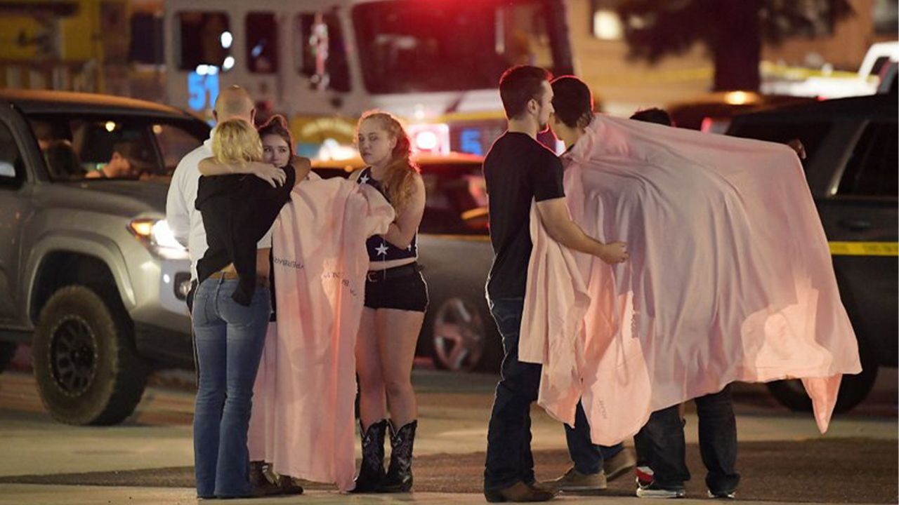 FILE - In this Thursday, Nov. 8, 2018, file photo, people comfort each other as they stand near the scene in Thousand Oaks, Calif., where a gunman opened fire Wednesday inside a country dance bar crowded with hundreds of people on "college night." (AP Photo/Mark J. Terrill)