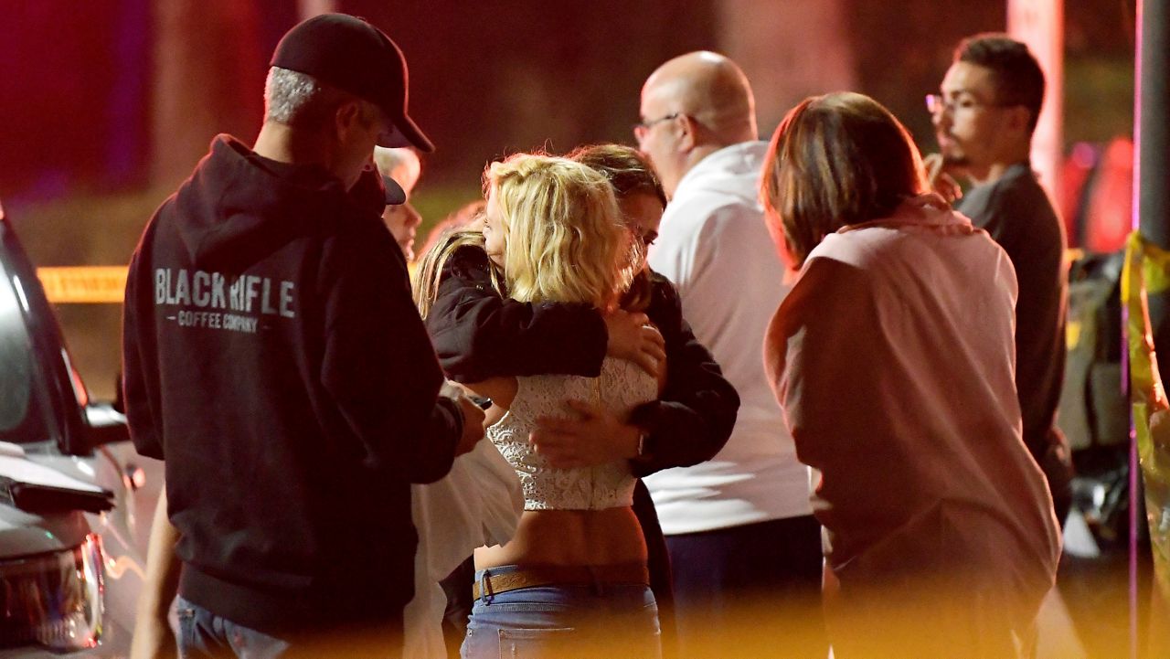 In this Nov. 8, 2018, file photo, people comfort each other as they stand near the scene of a shooting in Thousand Oaks, Calif., where a gunman opened fire inside a country dance bar crowded with hundreds of people. (AP Photo/Mark J. Terrill, File)