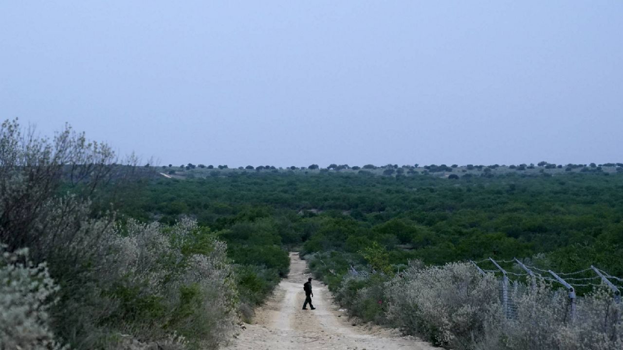 A Border Patrol agent walks along a dirt road near the U.S.-Mexico border Tuesday, May 11, 2021, in Roma, Texas. (AP Photo/Gregory Bull)