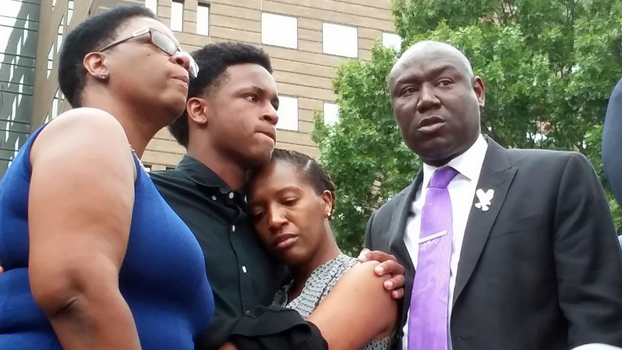 In this Sept. 10, 2018 file photo, Brandt Jean, center left, brother of shooting victim Botham Jean, hugs his sister Allisa Charles-Findley, during a news conference about the shooting of Botham Jean by Dallas Police Officer Amber Guyger, outside the Frank Crowley Courts Building in Dallas. He was joined by his mother, Allison Jean, left, and attorney Benjamin Crump, right. Guyger, who was fired soon after the shooting and charged with murder, said she mistook Jean’s apartment for her own. She was convicted in early Oct. 2019 — a rare jury decision — and sentenced to 10 years in prison. (AP Photo/Ryan Tarinelli, File)