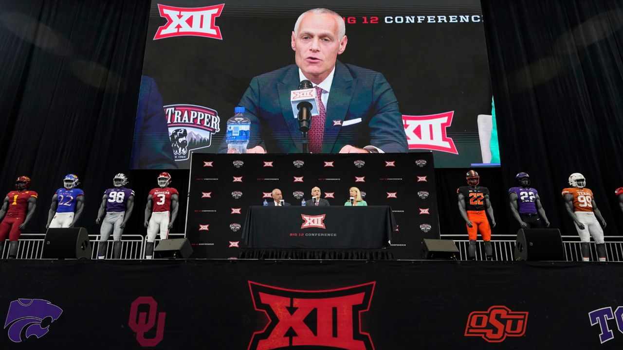 Incoming Big 12 Commissioner Brett Yormark, center, speaks with outgoing Commissioner Bob Bowlsby, left, and Baylor President Linda Livingstone looking on during a news conference opening the NCAA college football Big 12 media days in Arlington, Texas, Wednesday, July 13, 2022. (AP Photo/LM Otero)