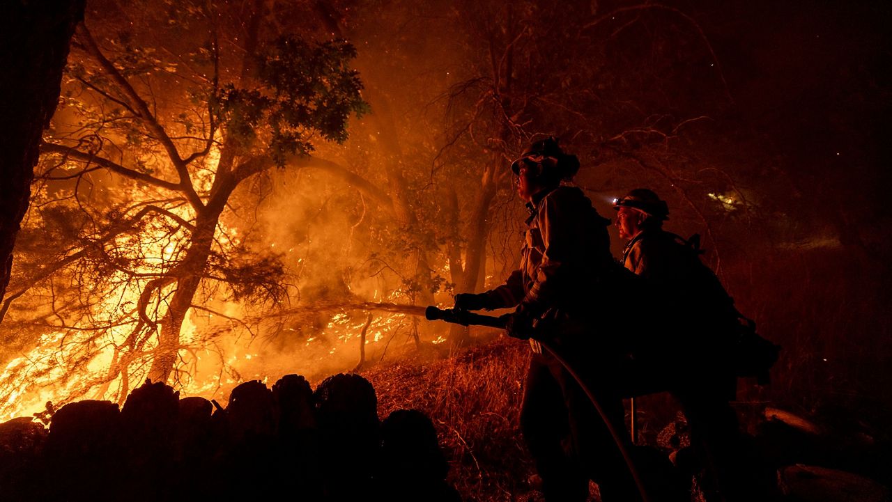 Firefighters establish a defense perimeter Tuesday around a house threatened by the Bridge Fire in Wrightwood, Calif. (AP Photo/Etienne Laurent)