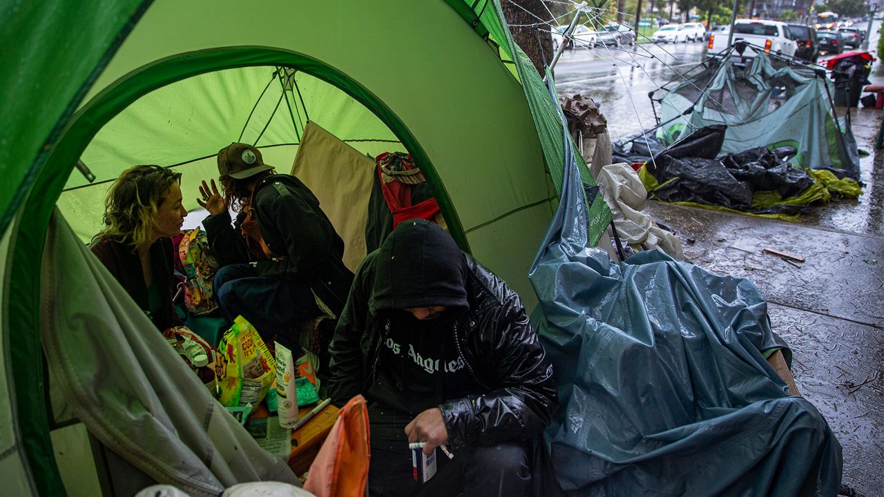 Photo shows homeless people huddled in a tent