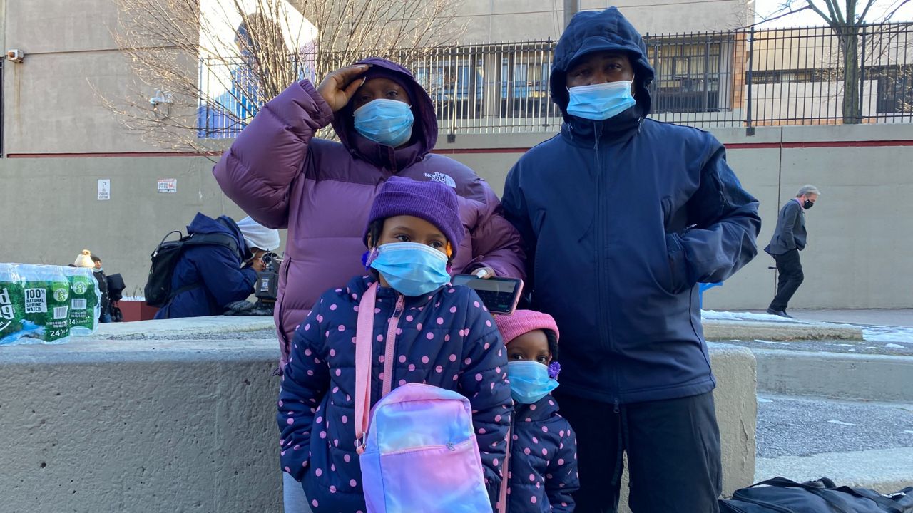 Fatima Woods and her family, which includes her two young daughters and their father, stand outside a school near the Twin Parks North West building.