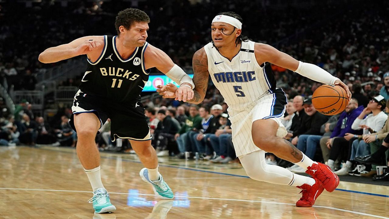 Orlando Magic's Paolo Banchero (5) drives to the basket against Milwaukee Bucks' Brook Lopez (11) during the first half of an NBA basketball game Wednesday, Jan. 15, 2025, in Milwaukee. (AP Photo/Aaron Gash)