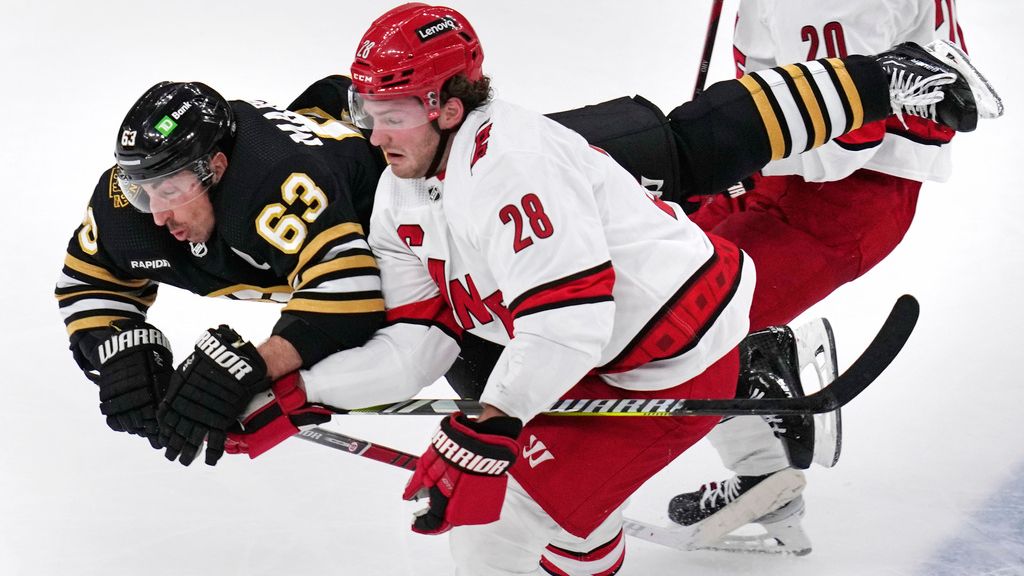 Boston Bruins left wing Brad Marchand (63) flies through the air after being tripped by Carolina Hurricanes left wing Brendan Lemieux (28) during the second period of an NHL hockey game, Wednesday, Jan. 24, 2024, in Boston. (AP Photo/Charles Krupa)