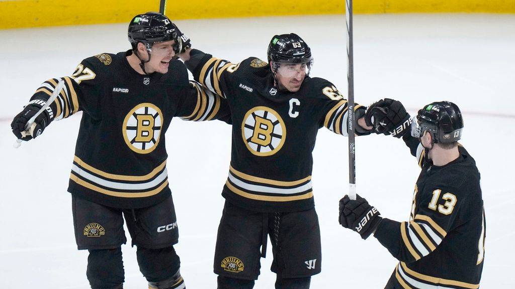 Boston Bruins left wing Brad Marchand (63) celebrates with defenseman Hampus Lindholm (27) and center Charlie Coyle (13) after scoring against the Vancouver Canucks during the first period of an NHL game Thursday, Feb. 8, in Boston. (AP Photo/Steven Senne)
