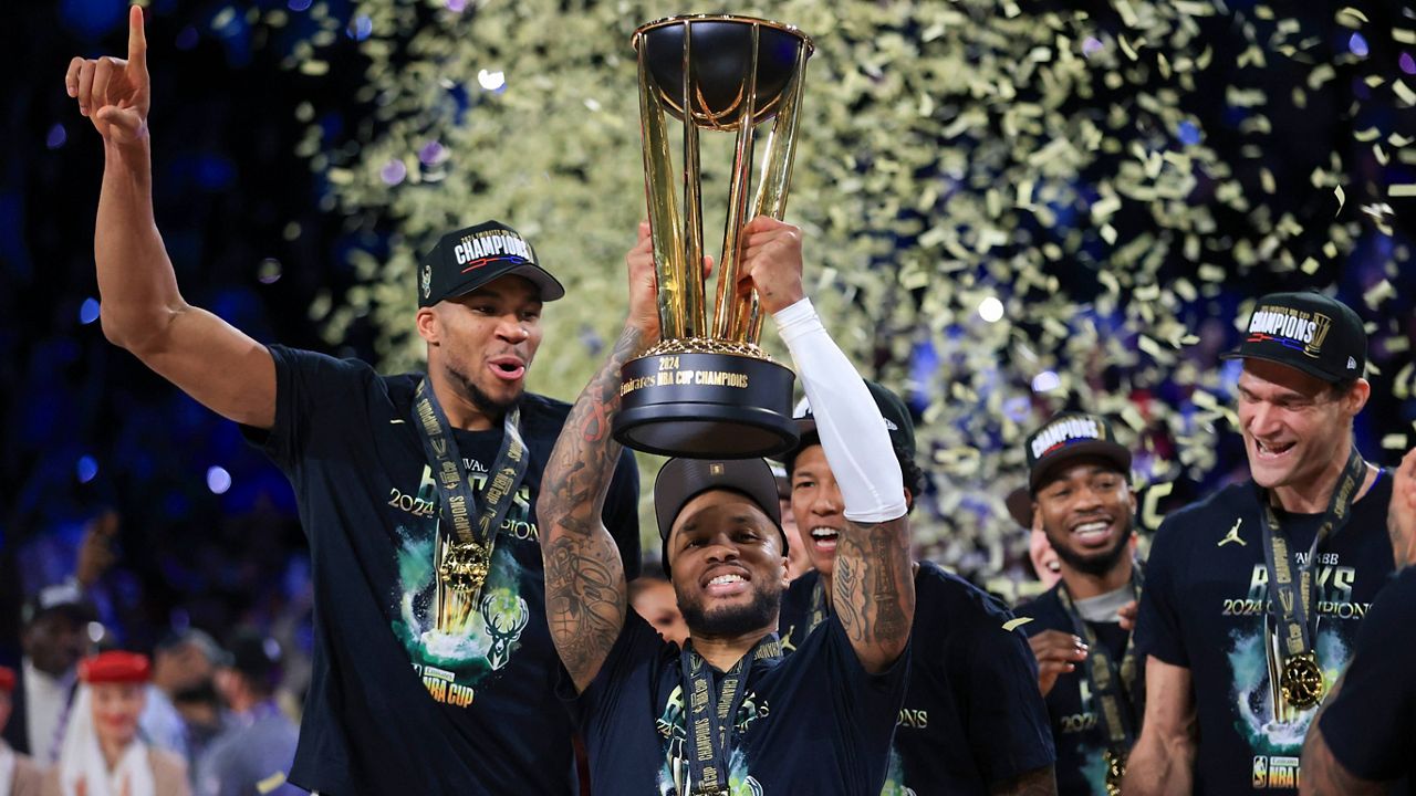 Milwaukee Bucks guard Damian Lillard (0) lifts up the NBA Cup while forward Giannis Antetokounmpo (34), left, and center Brook Lopez (11), right, celebrate after their team's victory in the championship game of the NBA Cup basketball tournament