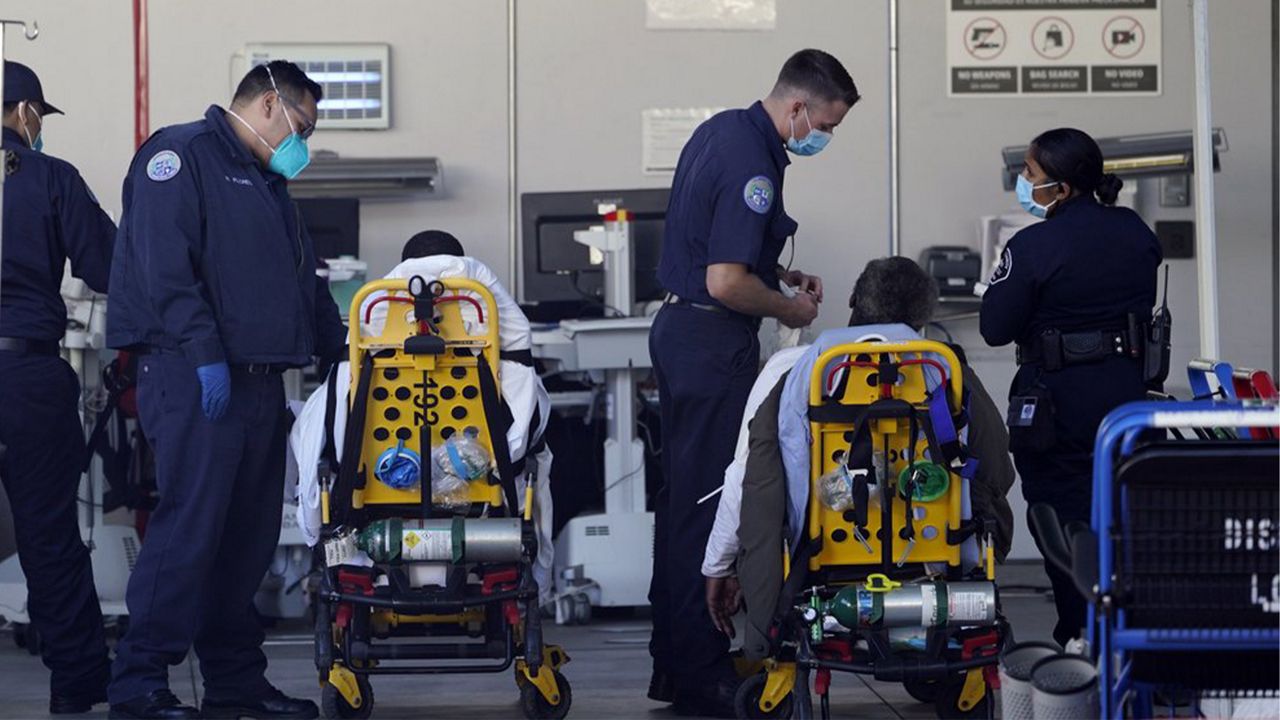 Los Angeles County emergency medical technicians deliver patients for admission at the Ambulatory Care Center station at the MLK Community Medical Group hospital in Los Angeles, Wednesday, Feb. 24, 2021. (AP Photo/Damian Dovarganes)