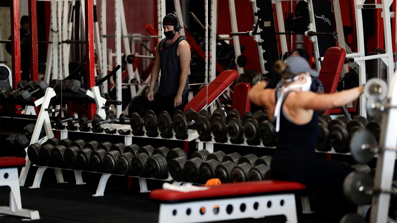 FILE - In this May 14, 2020, file photo, people work out at Metroflex Gym in Oceanside, Calif. California will allow schools, day camps, bars, gyms, campgrounds and professional sports to begin reopening with modifications starting Friday, June 12, 2020. (AP Photo/Gregory Bull, File)