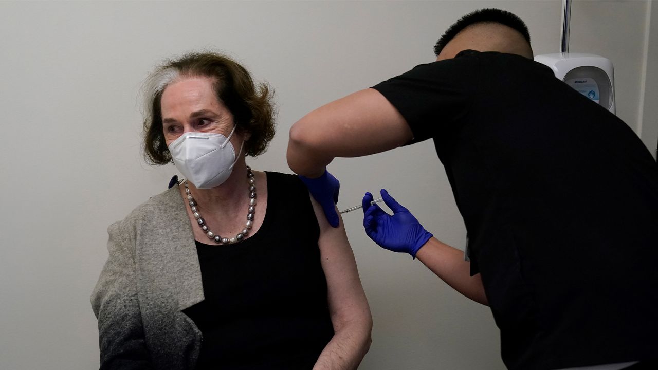 Licensed vocational nurse Aaron Wu, right, gives physician support senior analyst Helen Silacci the first of two Pfizer COVID-19 vaccinations at Seton Medical Center during the coronavirus pandemic in Daly City, Calif., Thursday, Dec. 24, 2020. (AP Photo/Jeff Chiu)