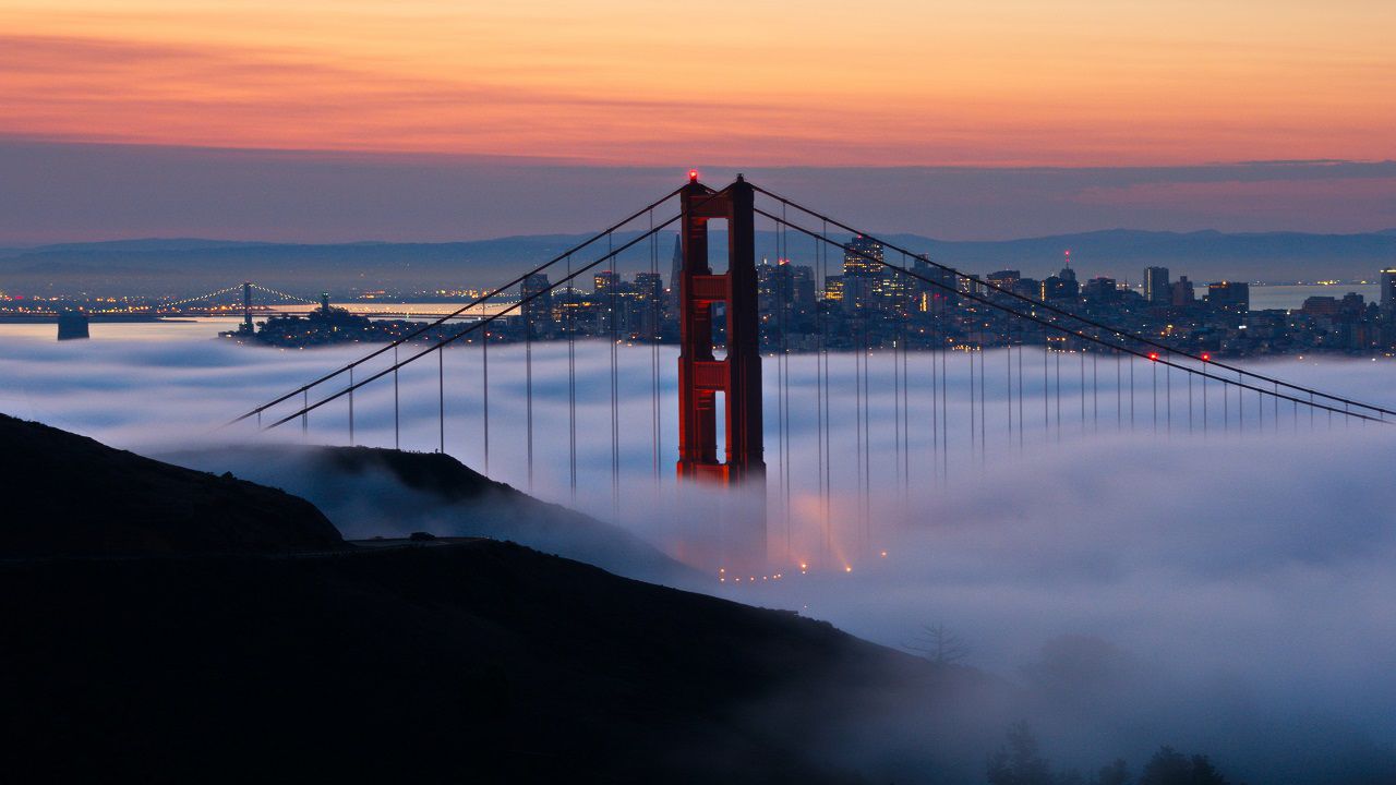 The Golden Gate Bridge peeks above a shallow layer of marine layer clouds.