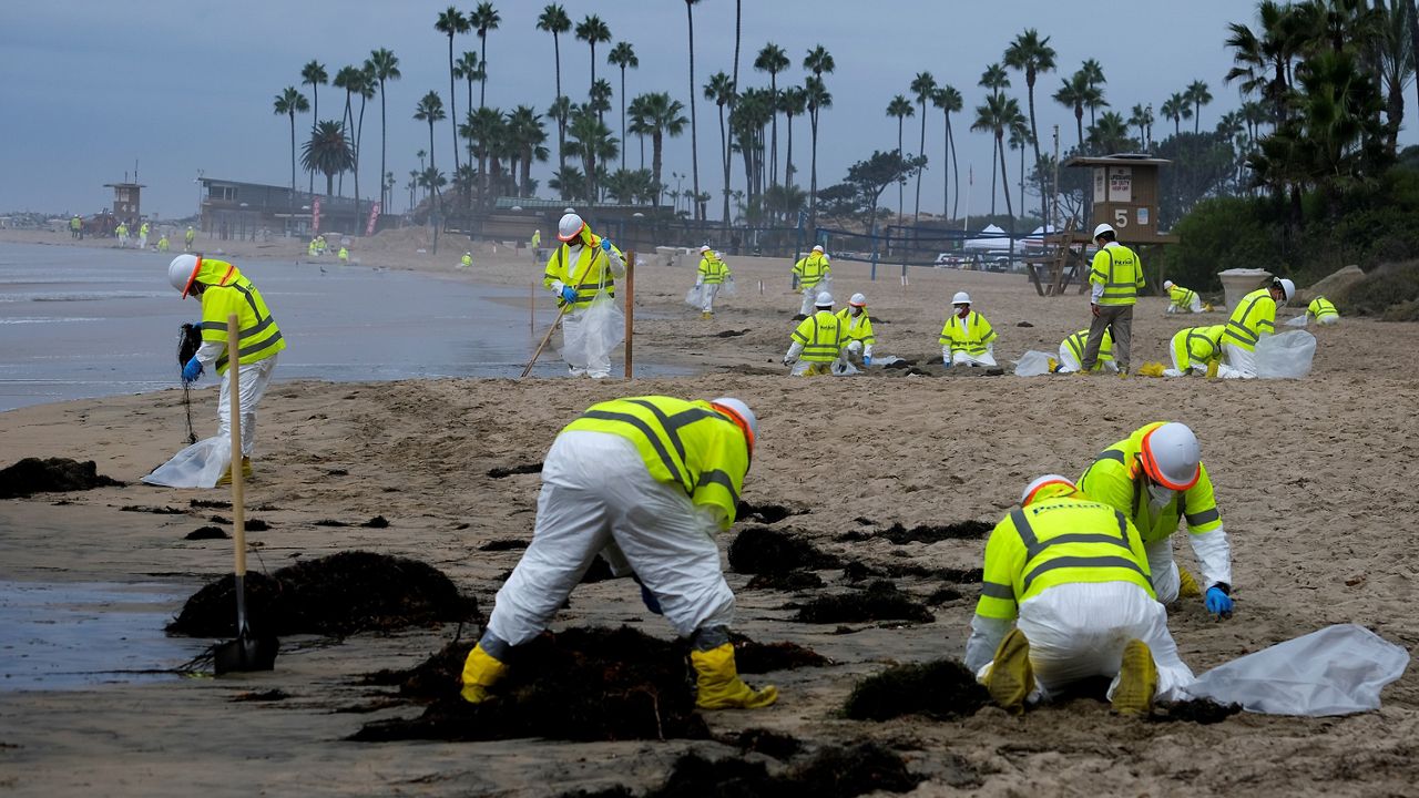 Workers in protective suits clean the contaminated beach in Corona Del Mar after an oil spill off the Southern California coast, on Oct. 7, 2021. 
