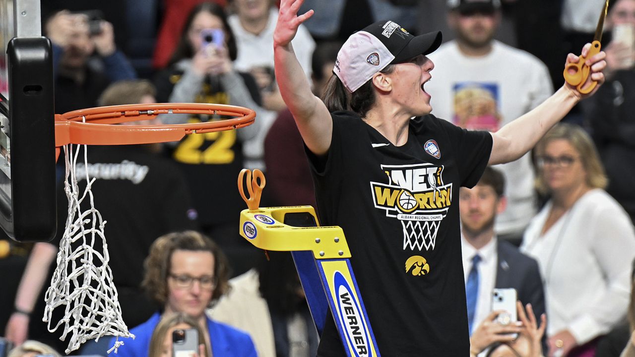 Iowa guard Caitlin Clark reacts to the crowd before cutting a piece of the net after Iowa defeated LSU in Albany on Monday night to reach the Final Four.