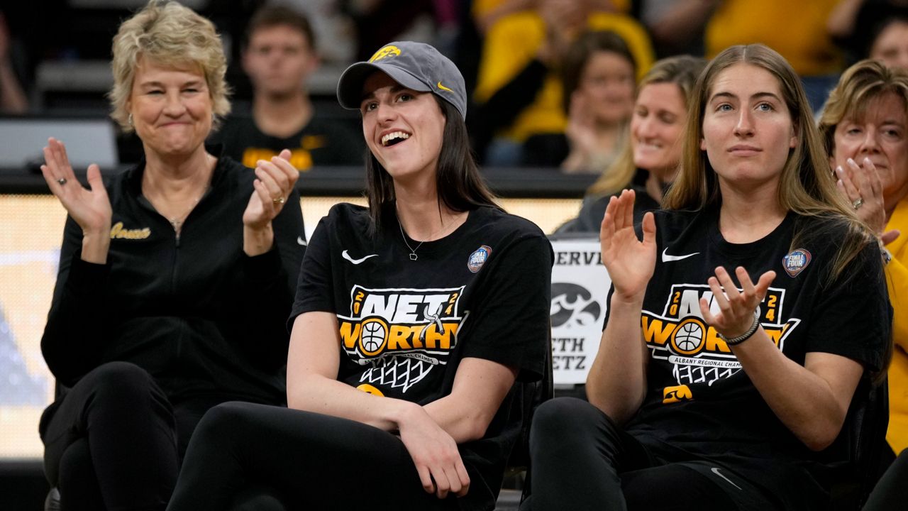 Iowa guard Caitlin Clark (center) sits with coach Lisa Bluder (left) and guard Kate Martin (right) as she finds out her number will be retired, during an Iowa women's basketball team celebration Wednesday, April 10, 2024, in Iowa City, Iowa. (AP Photo/Charlie Neibergall)