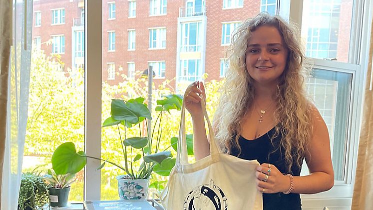 Climate change fashion designer holds a tote bag dyed using coffee grounds