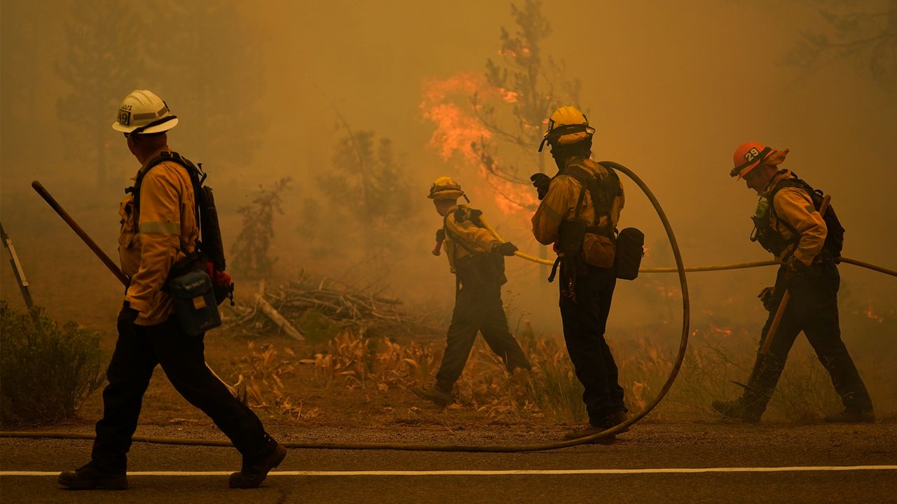 Firefighters carry water hoses while battling the Caldor Fire near South Lake Tahoe, Calif., Tuesday, Aug. 31, 2021. (AP Photo/Jae C. Hong)