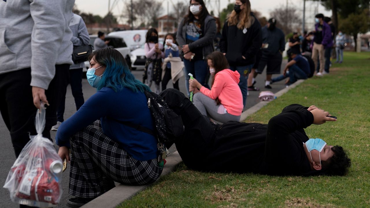 Robert Rodriguez, 14, looks at his phone while waiting in line for a test at a mobile COVID-19 testing site in Paramount, Calif., Wednesday, Jan. 12, 2022. (AP Photo/Jae C. Hong)