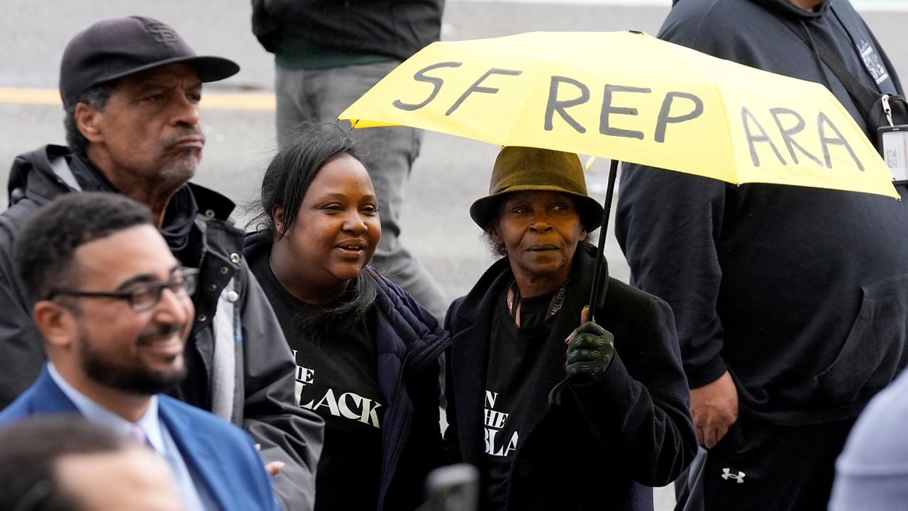 Pia Harris, with the San Francisco Housing Development Corporation, second from left, and her mother, Adrian Williams, listen to speakers at a reparations rally outside of City Hall in San Francisco, Tuesday, March 14, 2023. (AP Photo/Jeff Chiu, File)