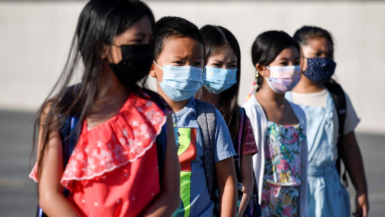 Masked students wait to be taken to their classrooms at Enrique S. Camarena Elementary School, Wednesday, July 21, 2021, in Chula Vista, Calif. (AP Photo/Denis Poroy, File)