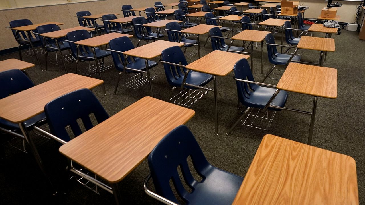 In this Aug. 18, 2020 file photo, math teacher Doug Walters sits among empty desks as he takes part in a video conference with other teachers to prepare for at-home learning at Twentynine Palms Junior High School in Twentynine Palms, Calif. (AP Photo/Gregory Bull, File)