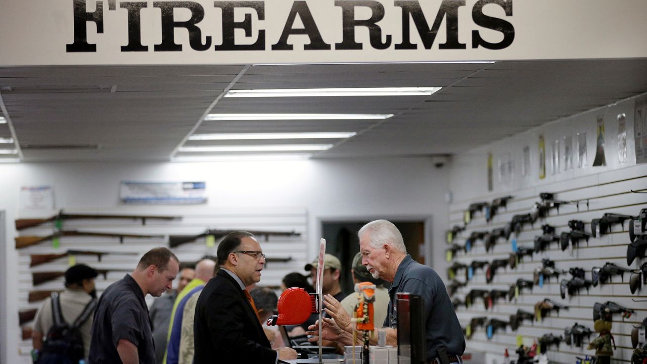 In this Dec. 9, 2015, file photo, sales associate Mike Conway, right, shows Paul Angulo guns at Bullseye Sport gun shop in Riverside, Calif. (AP Photo/Jae C. Hong)