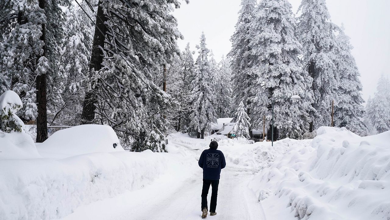 A local resident who declined to give his name walks to his home in Running Springs, Calif., Tuesday, Feb. 28, 2023. (AP Photo/Jae C. Hong)