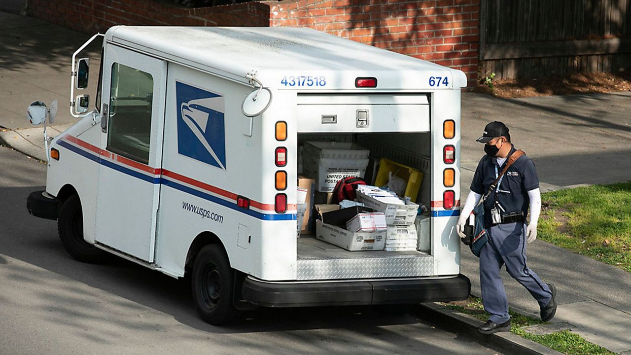 A mail carrier wearing a mask and gloves in Berkeley on March 27, 2020. Postal employees are considered essential during the shelter in place. Photo by Anne Wernikoff for CalMatters
